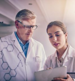 Shot of two focused scientists working together solving equations on a glass wall in a laboratory.